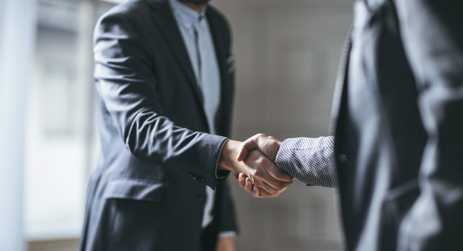 Two cropped businessmen handshaking.