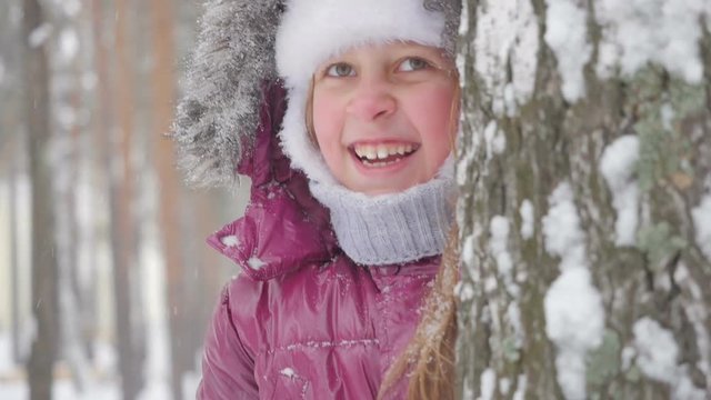 Happy child playing with snow in winter forest.
