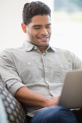 Man sitting on sofa and using laptop in living room