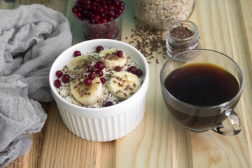 oatmeal with fresh banana slices, cranberries and flax seed and cup of black coffee