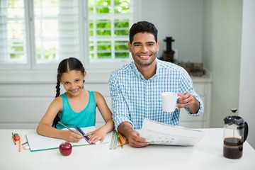 Daughter doing her homework near father 