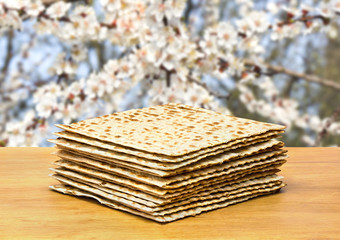 Matzo on the wooden table on background of blooming trees in garden