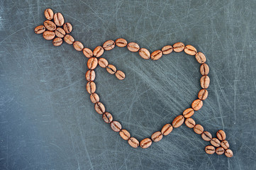 Heart with cupid arrow made of coffee beans on a dark background.