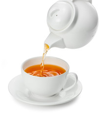 Tea being poured into tea cup isolated on a white background