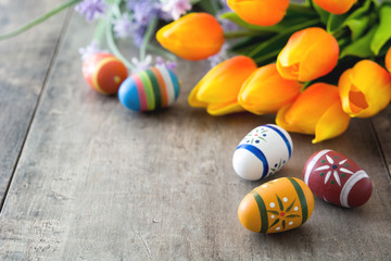 Easter eggs and tulips on wooden table
