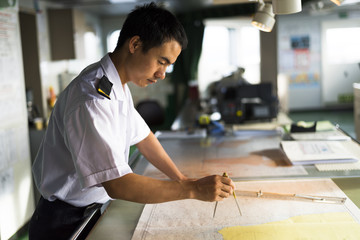 Young Chinese Navigator Doing Chartwork on Bridge