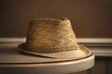 The window light is shining on the straw hat on the table