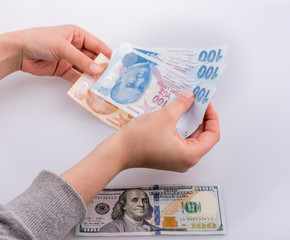 Hands holding Turksh Lira banknotes by the side of American doll