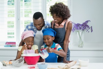 Obraz na płótnie Canvas Parents and kids preparing food in kitchen