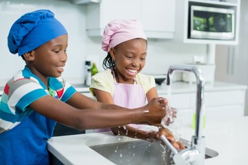 Siblings washing hand in kitchen at home