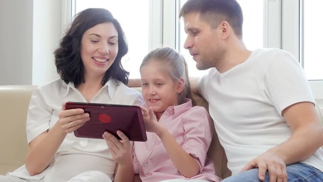 Family using digital tablet. Parents showing digital tablet to their daughter at home.