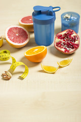 Fitness and healthy life concept. Fruits and nuts on a wooden table. Fitness equipment. Shaker and supplement measuring tape on a table.