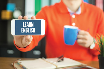 Young man showing smartphone and LEARN ENGLISH word concept on s