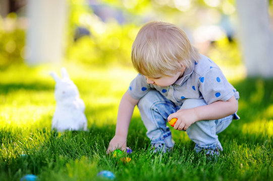 Little boy hunting for easter egg in spring garden on Easter day
