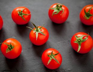 Fresh cherry tomatoes on a black background. Top view with copy