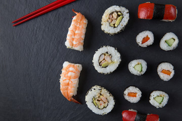 Sushi platter with chopsticks on dark background