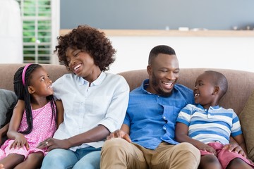 Parents and kids interacting while sitting on sofa 