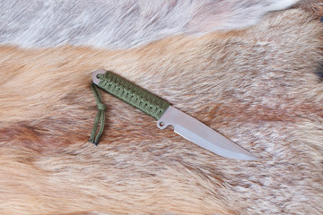 sharp hunting knife lies on the skin of a Fox
