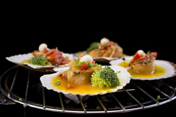 seared scallops with broccoli on black background.