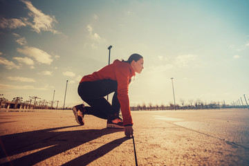 Sportswoman in ready position to run.Girl on the knee, preparing to start jogging.Achievements and...