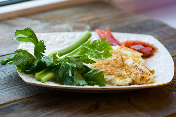 scrambled eggs with green celery on a white plate