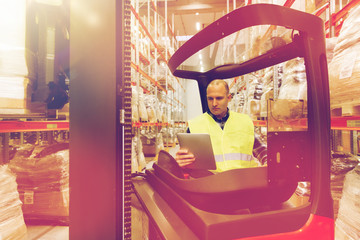 man with tablet pc operating forklift at warehouse