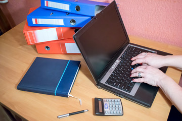 Hands of woman wearing smartwatch on the keyboard of her laptop