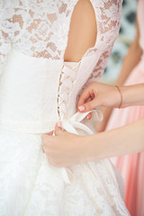 Obraz na płótnie Canvas bridesmaid tying bow on wedding dress