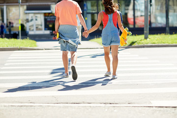 teenage couple with skateboards at city crosswalk