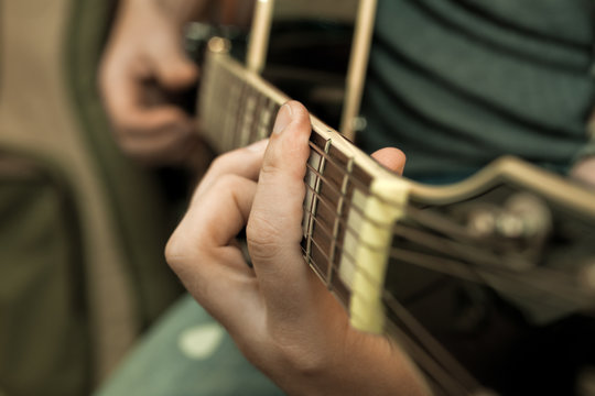 Musician's fingers on the strings of a guitar closeup