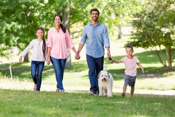 Happy family enjoying together with their pet dog in park