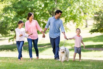 Obraz premium Happy family enjoying together with their pet dog in park