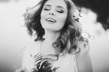 Beautiful bride with a bouquet of different flowers on background lake. Rustic Wedding