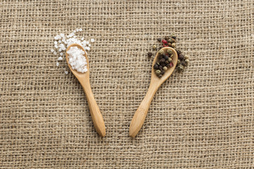 salt crystals and pepper beans on wooden spoons on canvas