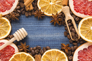 grapefruit and orange slices with coffe, cinnamon, star anise and wooden honey dipper on blue wooden background. Copy space