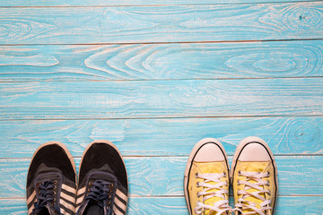 Yellow and blue sneakers stand together on blue wooden backgroun