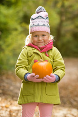 Cute Little Girl Holding a Pumpkin in the Woods