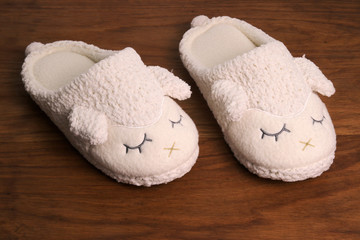 Women's slippers with a view of sheep on a wooden floor
