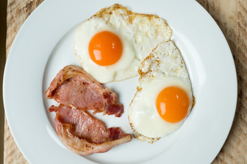 Overhead of Bacon and Eggs in Plate on Wooden Surface