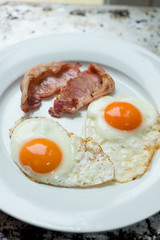 Cooked Bacon and Eggs in White Plate