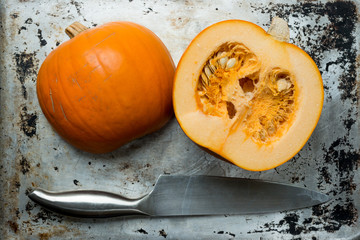 Pumpkin Halves and Knife on Grunge Aluminium Surface