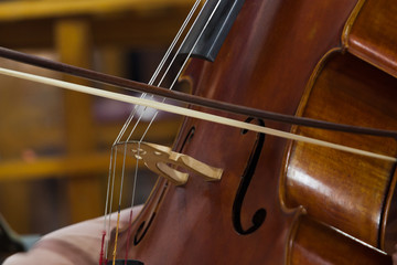 The bow on the strings of the cello closeup 