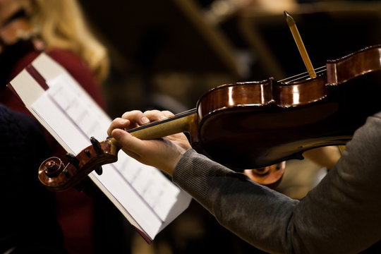 Hands musician playing the violin in the orchestra in dark colors
