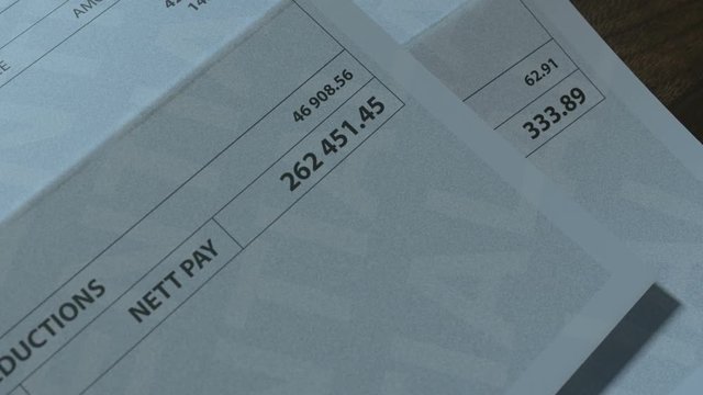 A pan and rack focus shot showing  two fictitious paychecks with a huge difference in the nett pay highlighting the income inequality created by capitalism