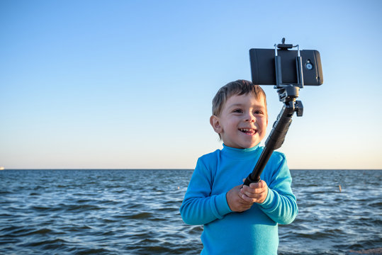 Young boy doing a selfie at the beach, kid happy and smiling loo