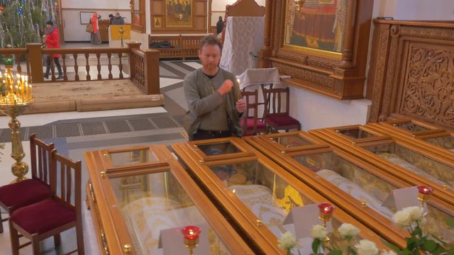 a Man Crosses Himself and Kisses a Glass Box, Which Has the Remnats of Some Christian Saint, While Being Inside of a Christian Orthodox Church