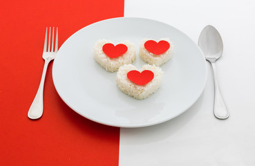 cooked rice heart shapes with a spoon and fork on white dish