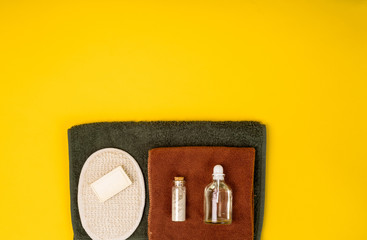 Spa or wellness setting in white colors. Bottles with essential aroma oil, towels, soap on yellow background.