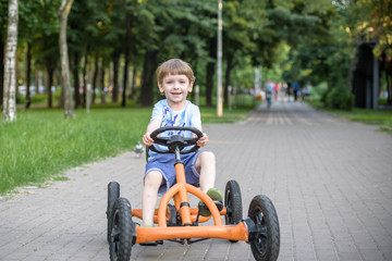 Little preschool boy driving big toy sports car and having fun, outdoors.