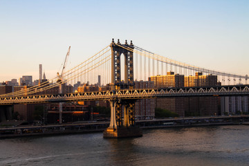 Obraz premium Manhattan bridge over the river and buildings before sunset, New York